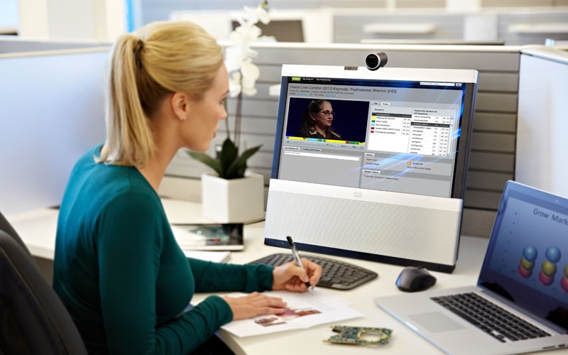 Woman sitting at desk using desktop and laptop Cisco devices