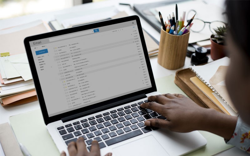 Woman using laptop with email inbox displayed