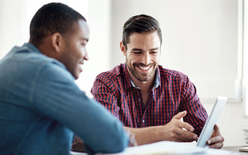 Two business colleagues use mobile tablet device 
