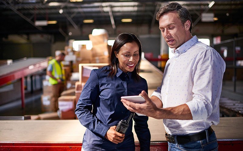 Two business colleagues use mobile tablet device 