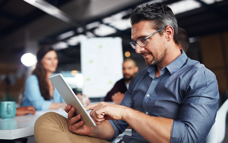 Two business colleagues use mobile tablet device 